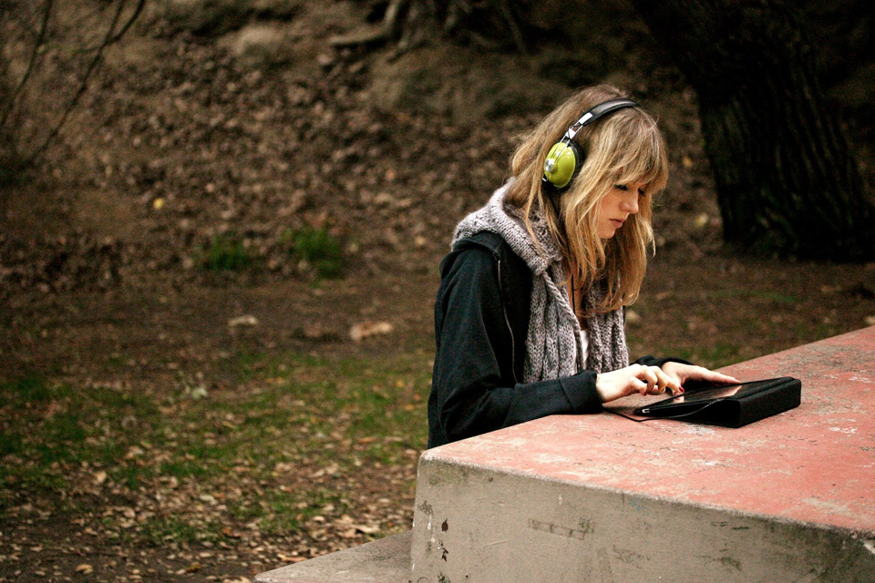 Early Polychord photo shoot: a musician with green headphones playing Polychord on an iPad at a park bench